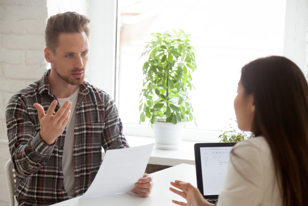 A person and another person sitting at a table talking to each other.